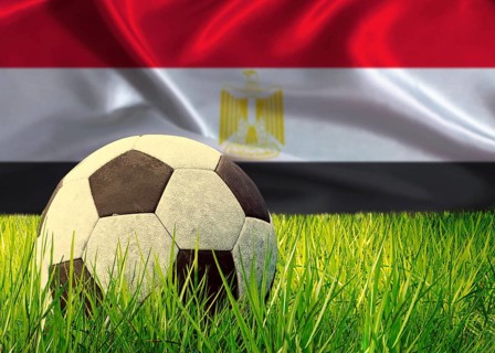 Soccer ball on the grass with Egypt flag in the background. Soccer ball on pitch against Egyptian