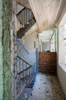Construction site featuring a partially demolished wall, exposed brickwork, and a blue safety net.