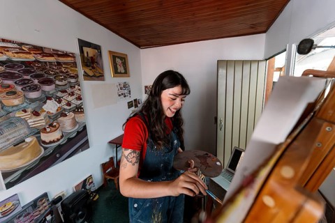 A young Latin woman engrossed in painting on a canvas in her home studio, surrounded by vivid