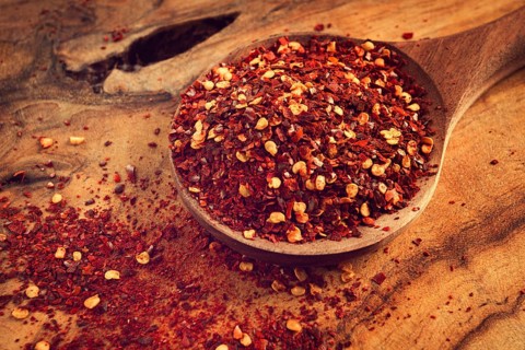 Red pepper flakes, in a wooden spoon, on a wooden table, rustic style, no people