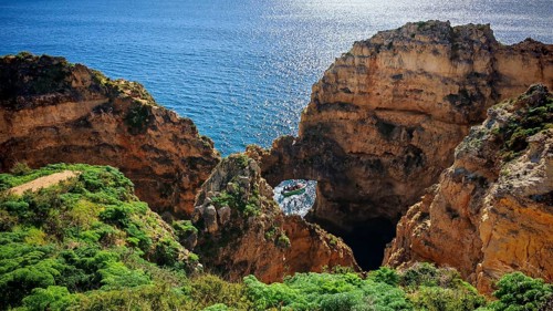 Cliffs and a cave with a boat in turquoise water against breathtaking scenery, Ponta da Piedade,