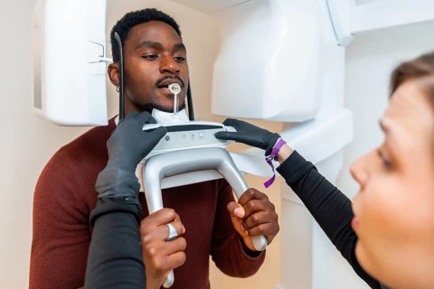 Dentist preparing a panoramic dental x ray scan for a male patient in a modern dental clinic