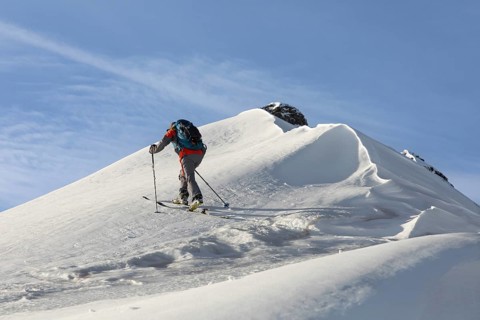 A skier tackles a snowy mountain slope with ski poles and backpack, capturing the essence of ski