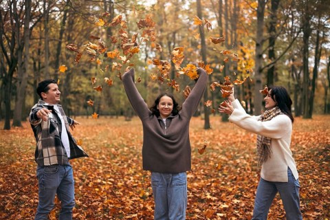 A joyful family playing in a park, tossing vibrant autumn leaves. The scene captures the spirit of