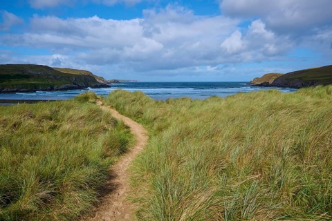 A trail snakes through grassy dunes overlooking the sea, Farr Bay, Bettyhill, Thurso, Scotland,