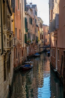 Narrow canal with boats, houses reflected in the water, Venice, Veneto, Italy