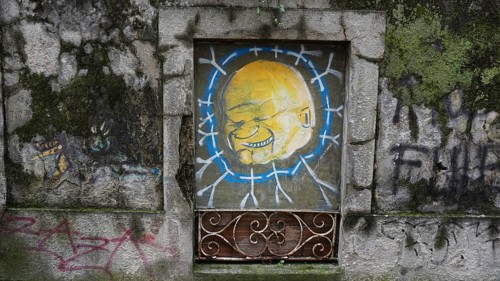 Graffiti of a yellow face on an old, painted wall in an urban environment, hiking on the Caminho