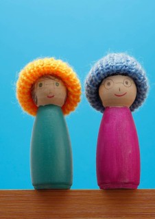 Two amusingly painted wooden cones with hats against a bright blue background, North