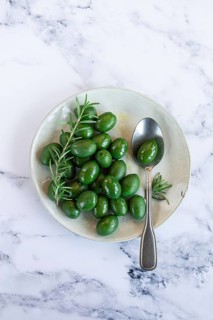 Chalkidiki olives, classic Greek green olive, on a plate, with a spoon, top view, no people