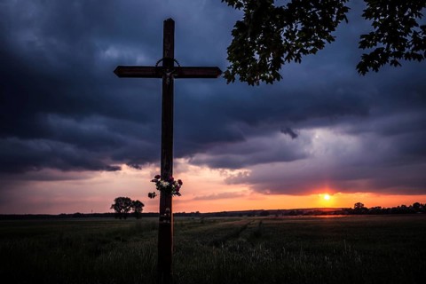 Wayside crucifix and sunset in the background in Tymowa, Poland