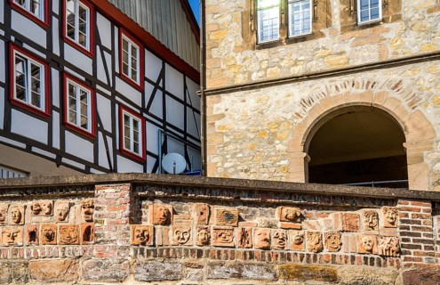 Artistic installation with mask and facial reliefs made of terracotta, in a historic brick wall,