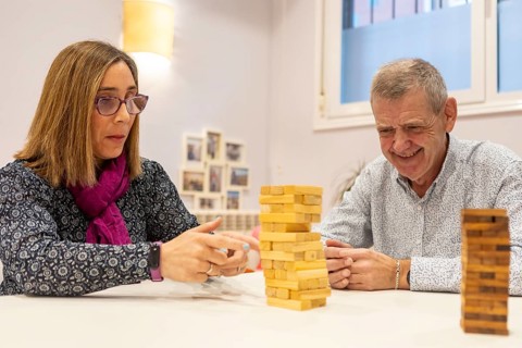 Couple with intellectual disabilities enjoy playing Jenga at supervised home. They are focused and