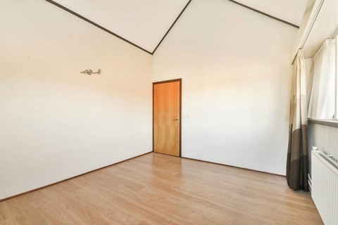 A clean and simple interior featuring wooden flooring, a door, and large windows allowing natural