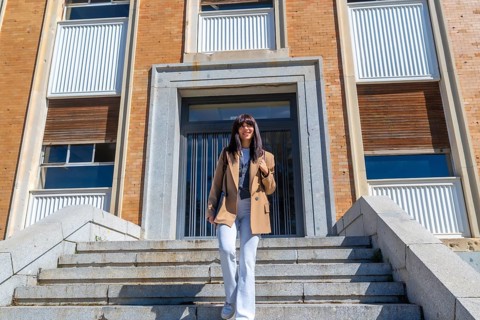 Young woman student smiling and confidently walking down the stone stairs of a university building,