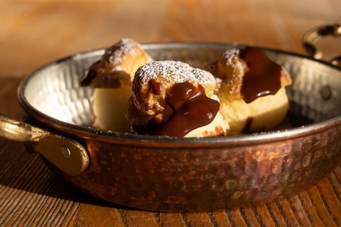 Delectable profiteroles filled with creamy ice cream and topped with rich chocolate sauce, dusted
