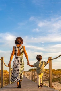 Mother and son enjoying a family vacation, walking hand in hand along a wooden boardwalk through