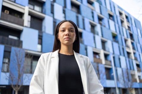 A confident Hispanic businesswoman stands strong in an urban environment, with modern architecture