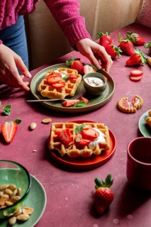 Delicious waffles topped with fresh strawberries and yoghurt on a rustic table. A romantic,