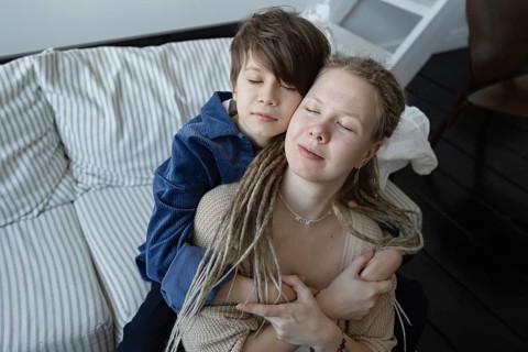 A serene moment depicting a mother and child embracing lovingly on a couch Both have their eyes