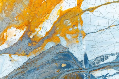 A captivating abstract image showcasing multicolored mud with striking orange, blue, and white hues