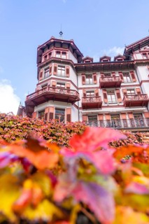 Detailed facade of a hotel with red balconies and autumn leaves, blue sky, Grandhotel Giessbach,