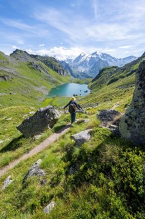 Mountaineer on hiking trail in picturesque mountain landscape, view of mountain lake Lac du Louvie