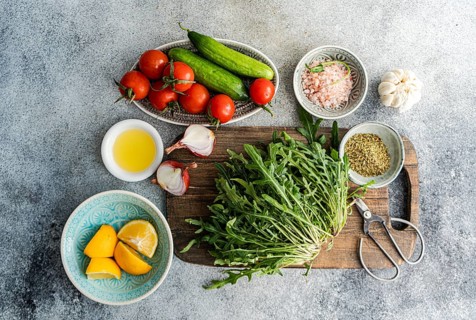 A vibrant display of healthy lunch ingredients including fresh rocket, chopped oregano, cherry