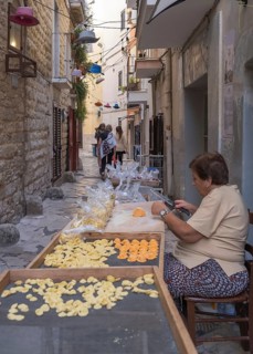 A pasta maker at work in the famous Strada del Orecchiette, historic centre of Bari Vecchio,