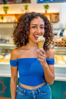 Vertical three quarter length photo of a sensual latin woman licking ice cream in store