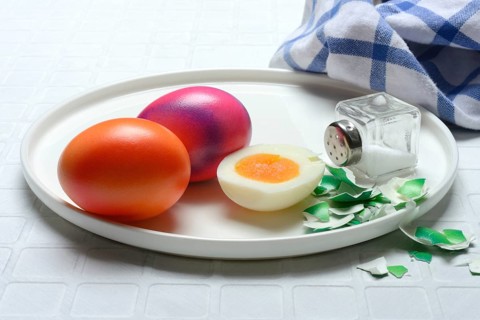Easter eggs and salt shaker on plate, partially peeled