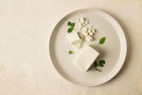 Cheese briquette for salads, Danish, white, top view, on a white plate