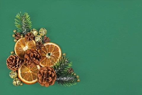 Christmas arrangement with dried orange slices, fir branches and cones and golden bells on dark
