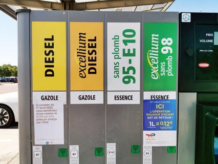 Petrol pump with nozzles for petrol and diesel at a motorway filling station in France, stickers