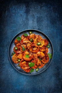 Grilled shrimp, unpeeled, headless, with spices, on a dark blue table, homemade, no people