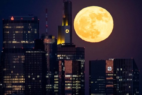 The full moon passes behind the Frankfurt banking skyline, Frankfurt am Main, Hesse, Germany