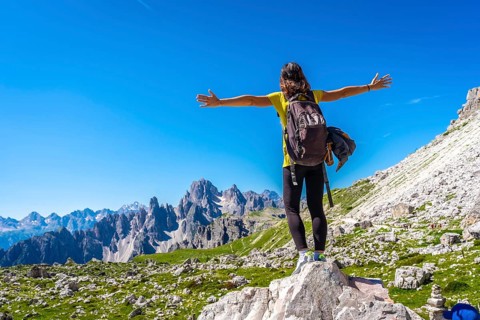 Hiker with open arms enjoying the breathtaking view of the tre cime di lavaredo, a symbol of the