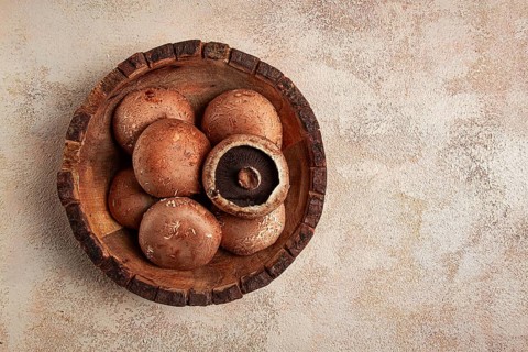 Fresh Portobello mushrooms, in a wooden bowl, top view, close-up, no people