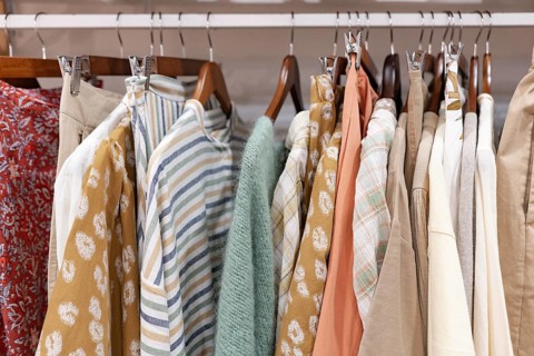 A collection of colorful clothes displayed on hangers of a clothes shop, featuring various textures