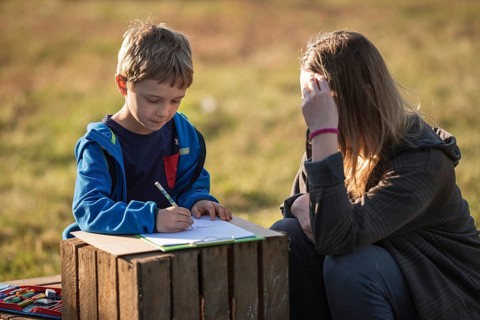 Little boy whit his Mom writing and learning in the garden bicouse school is closed due to Covid-19