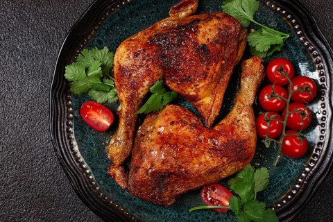 Grilled fried chicken legs, served with fresh cherry tomatoes and herbs, on a plate, homemade, no