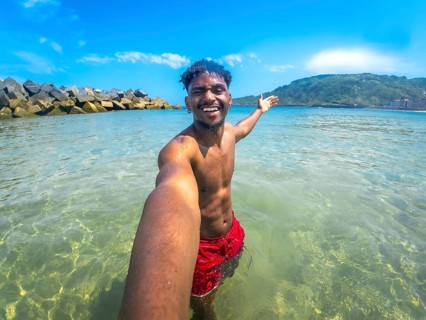 Young man taking a selfie while enjoying summer vacation in the ocean with clear water and blue sky