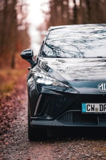 Detailed view of a black car with illuminated headlights in the forest, e-car sharing vehicle from