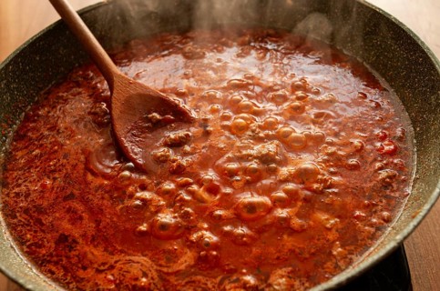 Cooking, bolognese sauce, in a frying pan, stirring with a wooden spoon, tomato meat sauce,
