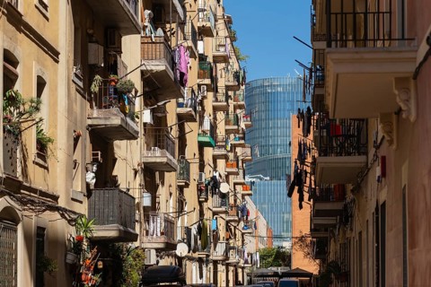 Narrow alley of houses in the Barceloneta neighbourhood, in the background modern skyscrapers in