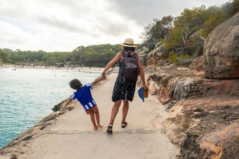 Mother and son enjoying summer holidays, walking along the scenic coast of s'amarador beach in