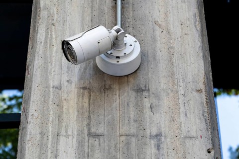 Security surveillance camera attached to a concrete pole, monitoring urban area, enhancing safety