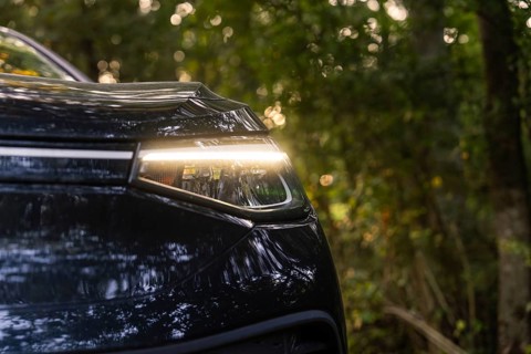 Close-up of the headlight of a car in the forest, reflecting light, natural environment, electric