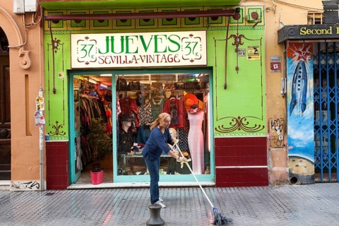 Woman mopping the street outside Jueves vintage clothes shop in Barrio Macarena, Seville, Spain