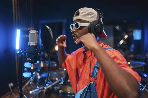Talented musician wearing headphones and stylish sunglasses, singing passionately into a microphone