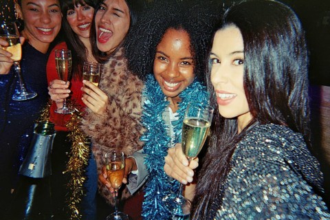 Diverse group of smiling young women friends celebrating together, holding champagne flutes and
